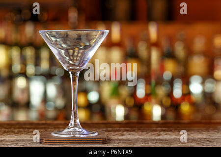 A cocktail glass on the background of a bar, an empty martini glass stands in a nightclub on a bar stand. Space for text Stock Photo