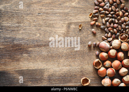 Different nuts on a wooden table. Cedar, cashew, hazelnut, walnuts and a spoon on the table. Many nuts are inshell and chistchenyh on a wooden backgro Stock Photo