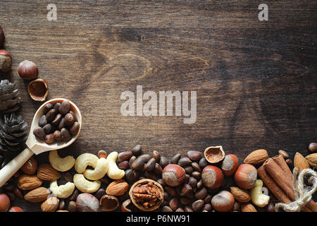 Different nuts on a wooden table. Cedar, cashew, hazelnut, walnuts and a spoon on the table. Many nuts are inshell and chistchenyh on a wooden backgro Stock Photo