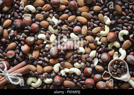 Different nuts on a wooden table. Cedar, cashew, hazelnut, walnuts and a spoon on the table. Many nuts are inshell and chistchenyh on a wooden backgro Stock Photo