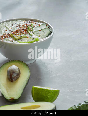 Healthy smoothies from lime, avocado, cucumber, and kiwi with flax seeds in a plate on a gray concrete background with copy space.. Healthy Vegetarian Stock Photo