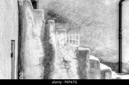 old stone stairs leading upwards with a plain wall and drainage pipe behind Stock Photo