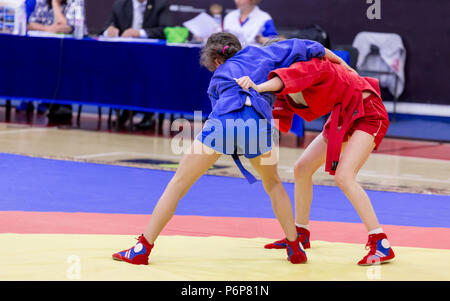 Two young girls compete in wrestling on tatami. Wrestling competition among kids. Teenage tournaments of martial arts and fighting sports. Stock Photo