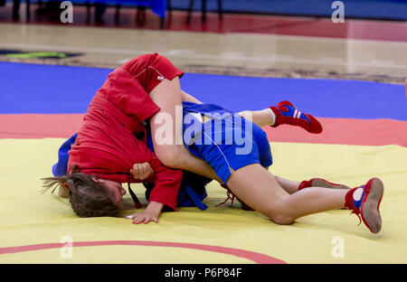 Two young girls compete in wrestling on tatami. Wrestling competition among kids. Teenage tournaments of martial arts and fighting sports. Stock Photo