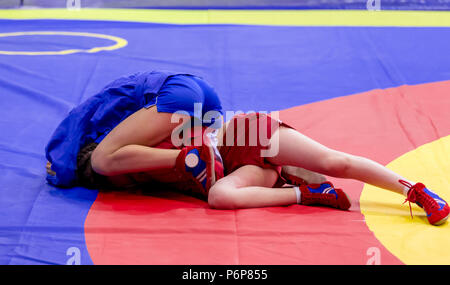 Two young girls compete in wrestling on tatami. Wrestling competition among kids. Teenage tournaments of martial arts and fighting sports. Stock Photo