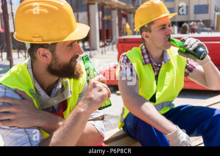 Two young workers drinking a cold beer during break at work Stock Photo