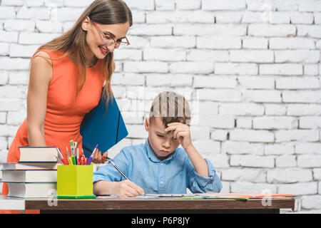 Student boy doing work in school supervised by his teacher Stock Photo