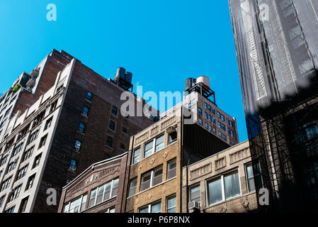 New York City, USA - June 20, 2018: Low angle view of old buildings and water towers against sky in Midtown of Manhattan Stock Photo