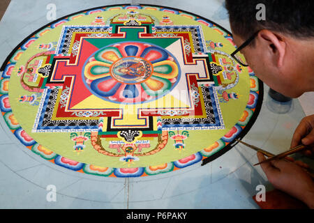 Tibetan monk working on sand mandala. Close-up. Stock Photo