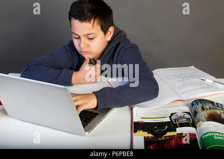 12-year-old schoolboy doing his homework with a laptop. Paris, France. Stock Photo