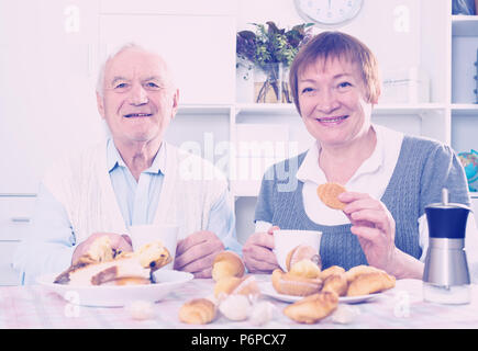 Smiling elderly husband and wife having breakfast and talking at table Stock Photo
