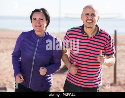 Happy active mature couple jogging together at sunny morning Stock Photo