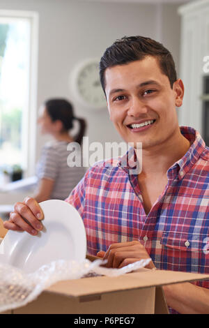 Portrait Of Young Couple Unpacking Boxes In Kitchen On Moving Day Stock Photo