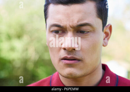 Outdoor Head And Shoulder Portrait Of Worried Young Man Stock Photo