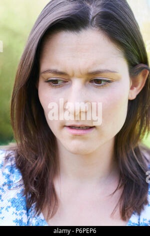 Outdoor Head And Shoulder Portrait Of Worried Young Woman Stock Photo