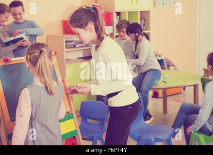 Smiling schoolgirls drawing a blackboard, children at lesson in class Stock Photo