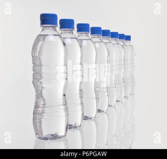 row of eight plastic water bottles disappearing into distance with focus on front bottles Stock Photo