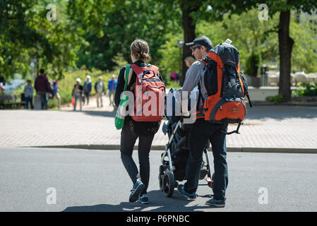 RIGA, LATVIA - JUNE 22, 2018: Tourists with a baby carriage and large backpacks view the city. Stock Photo