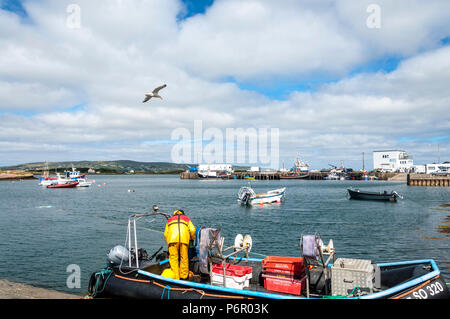 Burtonport, County Donegal, Ireland weather. 2nd July 2018. The warm weather continues with a cooling breeze in the harbour on Ireland's north-west coast. An inshore fisherman refuels his boat in foreground. Credit: Richard Wayman/Alamy Live News Stock Photo