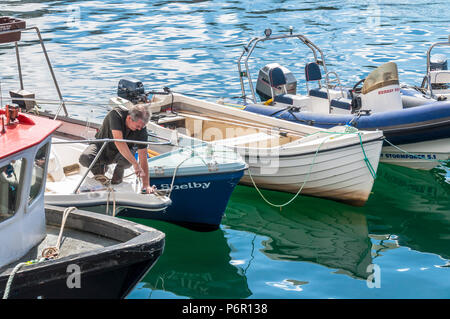 Burtonport, County Donegal, Ireland weather. 2nd July 2018. The warm weather continues with a cooling breeze in the harbour on Ireland's north-west coast. A man takes advantage of the hot day to fix his boat. Credit: Richard Wayman/Alamy Live News Stock Photo