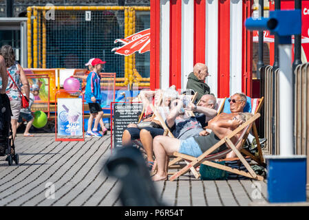 Skegness, UK. 2nd July 2018. On Skegness Pier a group of old age pensioners sit in their deck chairs and enjoy the hot weather, bright sunshine, and raising temperatures as they relax and take it easy during the current heatwave that is hiting the whole of the UK. Credit: Steven Booth/Alamy Live News. Stock Photo