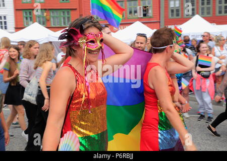 People wearing masks and sequin dresses in the colours of the LGBT flag march along Bryggen during the Bergen Pride 2018 parade in Bergen, Norway. Stock Photo