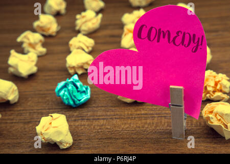 Word writing text Comedy Call. Business concept for Fun Humor Satire Sitcom Hilarity Joking Entertainment Laughing Clothespin holding pink heart paper Stock Photo