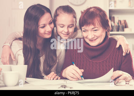 Three generations of happy family working together with documents at home Stock Photo