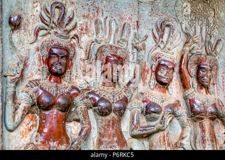 Four bas-relief carved female figures of Apsara dancers still show traces of original paint colours on a temple wall at Angkor Wat, Siem Reap, Cambodi Stock Photo