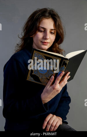 Young woman reading kuran. Paris, France. Stock Photo