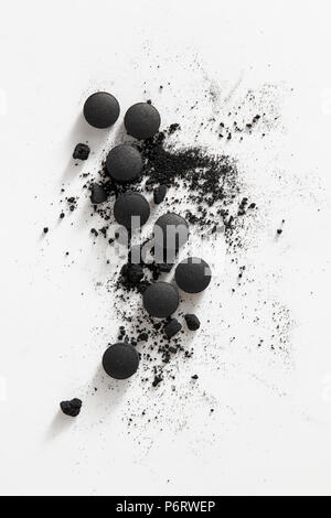 Activated charcoal tablets on a white background. Activated charcoal, also known as activated carbon, is a medication used to treat poisonings. Stock Photo