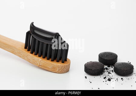 Toothbrush with black charcoal toothpaste. Black toothpaste on toothbrush with activated charcoal pills. Stock Photo