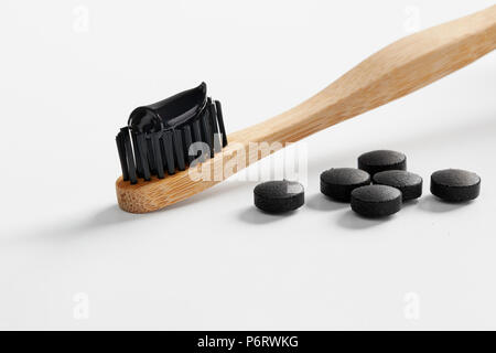 Toothbrush with black charcoal toothpaste. Black toothpaste on toothbrush with activated charcoal pills. Stock Photo