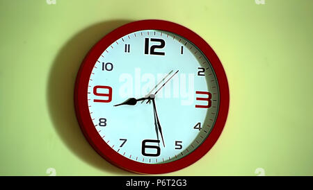 classic red round wall clock isolated on wall, interior house Stock Photo