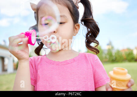 Cute Asian Girl Blowing Bubbles Outdoors Stock Photo