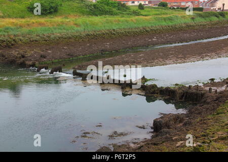 A broken water flow control dam crossing the river Avon at Aberavon in Port Talbot with slow water flow at low tide. Stock Photo