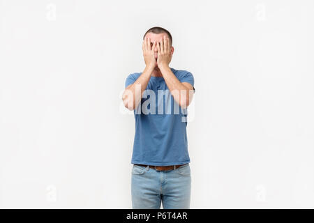 Studio portrait of hidpanic young man covering his face in dissapoint using facepalm sign Stock Photo