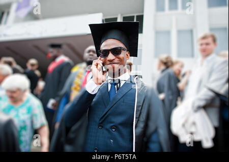 African american happy man at graduation. Graduated student speaking phone at crowd of people. Stock Photo