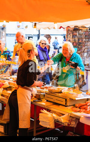 French bread being sold on market stall during Sandwich town's Le Weekend, French festival. Mature woman, paying stall holder for bread Stock Photo