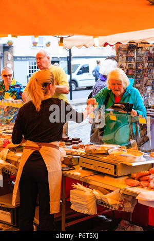 French bread being sold on market stall during Sandwich town's Le Weekend, French festival. Mature woman paying stall holder for bread with English £5 Stock Photo