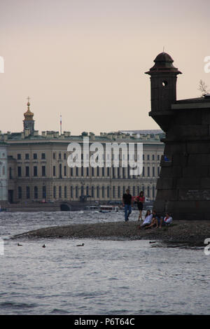 People enjoying a walk along the pebbled beach next to the Peter and Paul Fortress in St. Petersburg, Russia Stock Photo