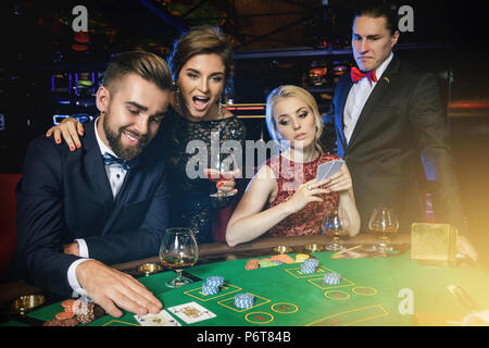 Losers and winners. Group of rich well-dressed people is playing poker in the casino. Concepts of luxury life Stock Photo