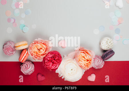 Composition of macarons and flowers in grey and pink colors with confetti. Flat lay. Place for your text. Stock Photo