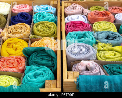 Foulards of various colors rolled up on the sales counter Stock Photo