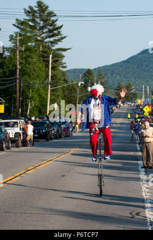 A happy clown dressed up in red, white and blue riding a unicycle in the 4th of July parade held on June 30, 2018 in Speculator, NY USA Stock Photo