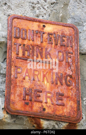 “Don’t even think of parking here”. Humorous No Parking message on a rusty textured old metal sign. Isle of Portland, Dorset, England, United Kingdom. Stock Photo