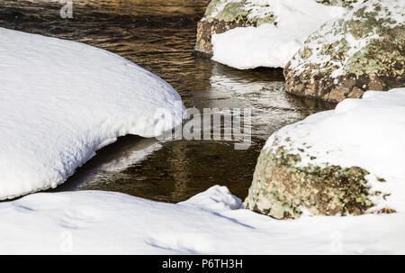 Close-up of river with snowy banks and rocks Stock Photo
