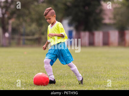 Boy kicking football on the sports field during soccer match Stock Photo