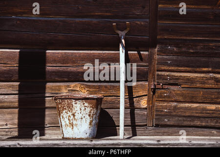 Old rusty metal bucket and mattock against weathered girder wall Stock Photo