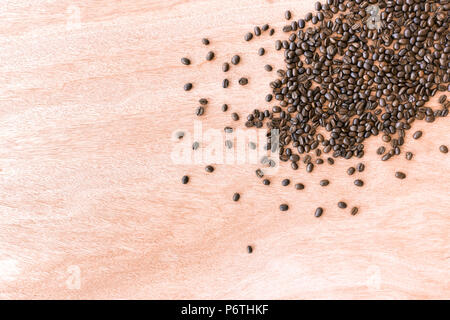 Roasted coffee beans scattered over a beautiful red brown wood background. Stock Photo